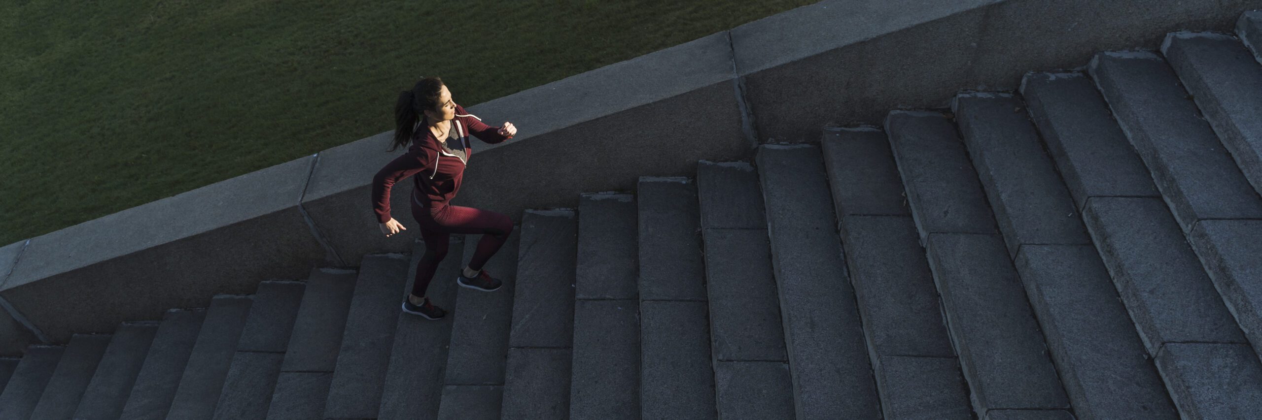 A woman in running clothes is climbing a set of concrete stairs as part of her fitness routine.
