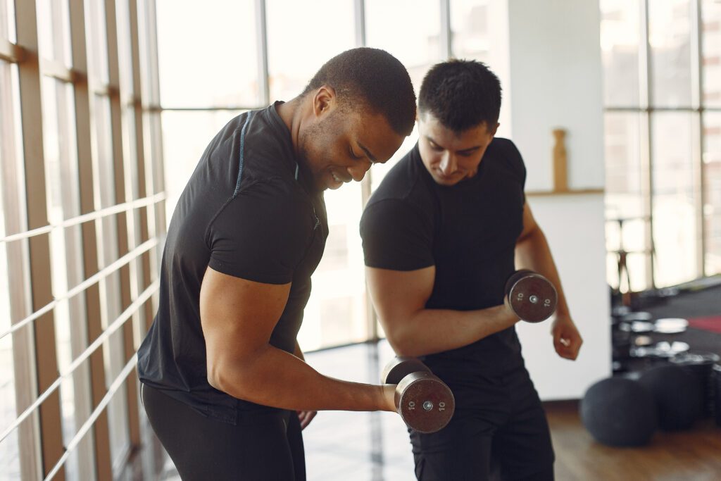 A personal trainer instructs his client on proper form when lifting free weights.
