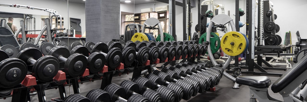 An image of free weights and gym equipment in a fitness facility.